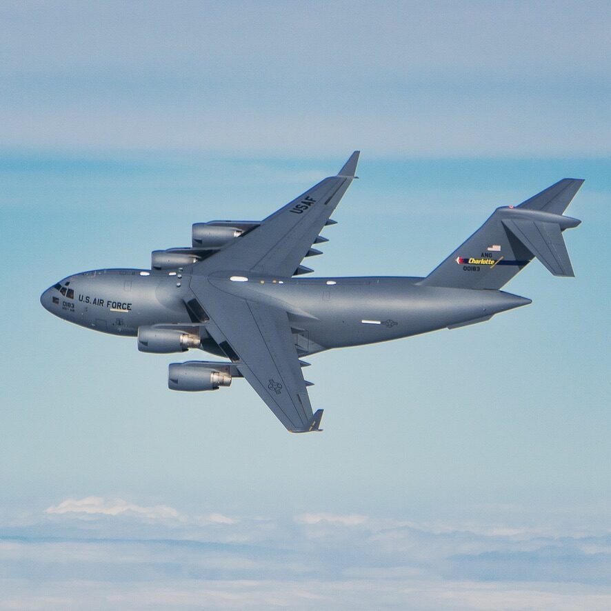 C-17 Globemaster III banking in flight against blue sky — U.S. Air Force Charlotte ANG