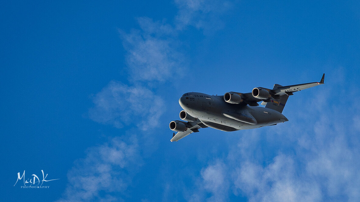 U.S. Air Force C-17 Globemaster III overhead against blue sky — be a guest on the Voice for Valor veteran podcast