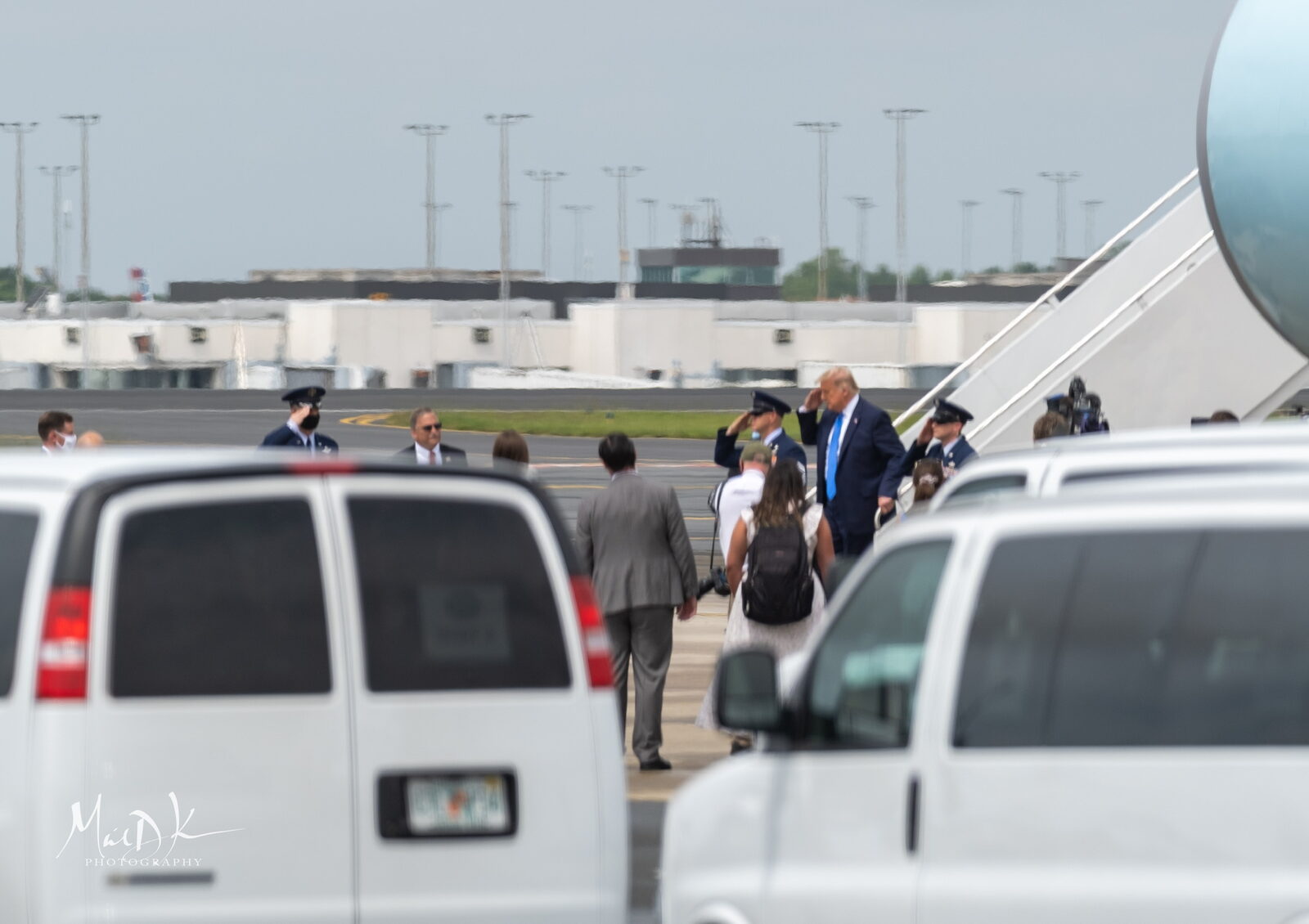President Donald Trump descends the steps of Air Force One, returning a salute from Air Force personnel, after arriving in Charlotte.