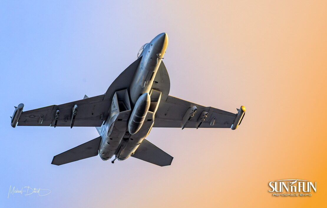 A U.S. Navy F/A-18 passes overhead against a sunset sky at the Sun 'n Fun Aerospace Expo.